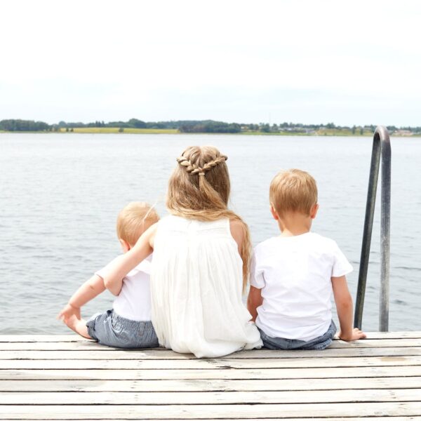 woman wearing white halter dress beside kid wearing white crew neck shirt near body of water