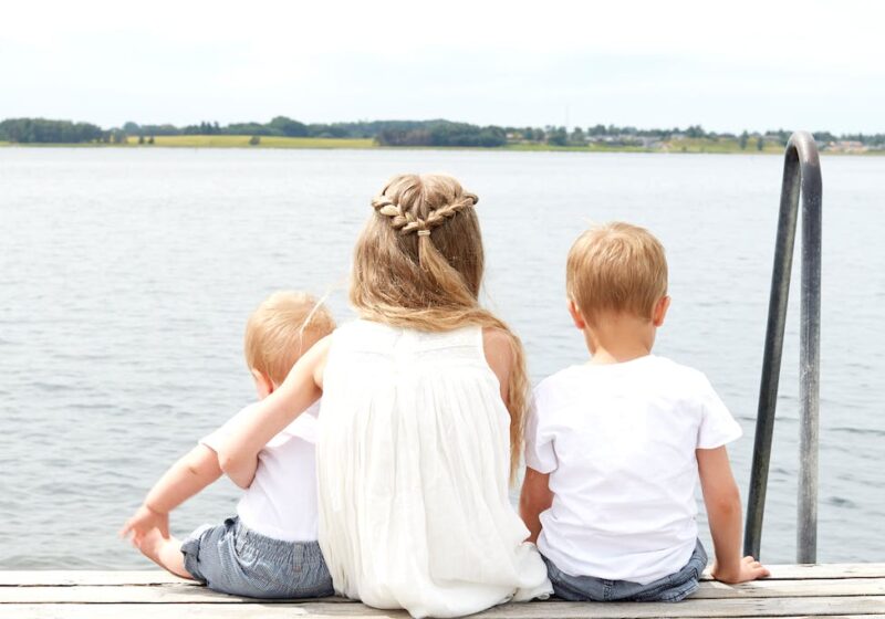 woman wearing white halter dress beside kid wearing white crew neck shirt near body of water