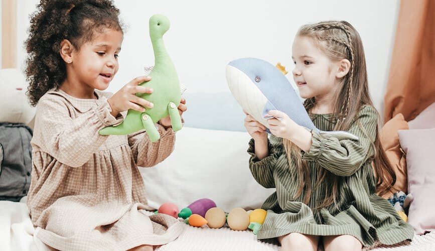 photo of two girls playing with stuffed animals